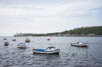 the boats are docked on the harbor near a large stone wall and lighthouses as well