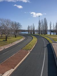 a curved road with a road leading to a lake in the background and an empty street next to it