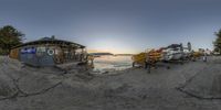 a group of boats parked on the beach at sunset in the bay area of a shore, with the sun in the distance