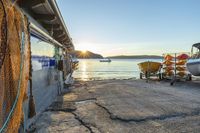 a fishing dock and boats at sunset with a boat docked on one end, in the background