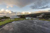 this is a view of the ocean from the top of a hill looking towards a parking space