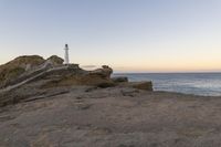 a lighthouse on the edge of a cliff overlooking the ocean and rocks in front of the light house