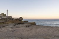 a lighthouse on the edge of a cliff overlooking the ocean and rocks in front of the light house