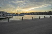 a person on a bench and some boats by a harbor at sunset at dusk time