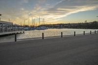 a person on a bench and some boats by a harbor at sunset at dusk time