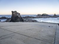 an empty path overlooking the water on the coast with rocky rocks in the foreground