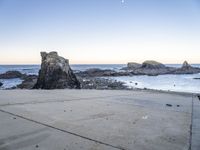 an empty path overlooking the water on the coast with rocky rocks in the foreground