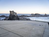 an empty path overlooking the water on the coast with rocky rocks in the foreground