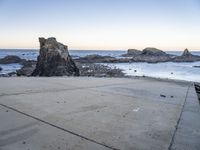 an empty path overlooking the water on the coast with rocky rocks in the foreground