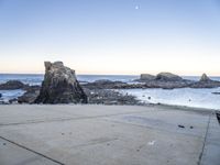 an empty path overlooking the water on the coast with rocky rocks in the foreground