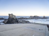 an empty path overlooking the water on the coast with rocky rocks in the foreground