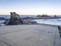 an empty path overlooking the water on the coast with rocky rocks in the foreground