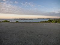 a man riding a skateboard across a parking lot next to a body of water