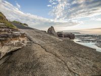 large rocks along the shore as the sun rises behind them on an autumn day with low clouds