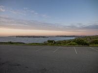 an empty parking lot at the beach at sunset with a view of the ocean and skyline