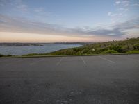 an empty parking lot at the beach at sunset with a view of the ocean and skyline