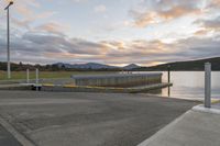 a parking dock and water reservoir on a lake with mountains in the distance during sunset