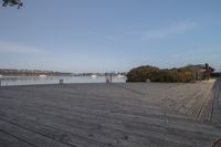 the wooden boardwalk next to the lake is very long in length and stretches across the area