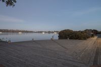 the wooden boardwalk next to the lake is very long in length and stretches across the area