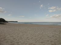 a view of the beach and ocean, from a distance in a distance is a beach house