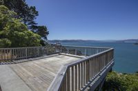 deck overlooking water, with trees and a wooden floor under a sunny blue sky on a sunny day