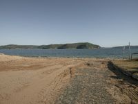 a deserted beach with a big body of water in the distance while several hills can be seen in the distance