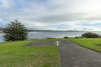 an empty park with an artificial grassy bench next to the ocean and sky and the water on the other side