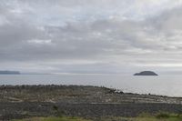 the view of some water from an island area, and rocks and gravel in front