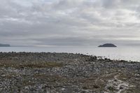 the view of some water from an island area, and rocks and gravel in front