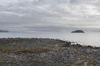 the view of some water from an island area, and rocks and gravel in front