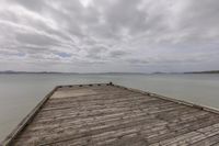 a cloudy day over the water and a wooden dock near a large body of water