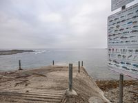 a parking lot next to the beach with an information sign in the background on a wet day