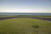 view of the ocean from a grassy area near an ocean front area with a curved path