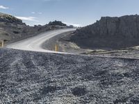 a curved dirt road leads down a mountain with a road sign in the foreground