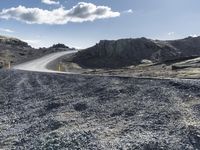 a curved dirt road leads down a mountain with a road sign in the foreground