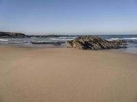 a beach covered in small rocks and water on a sunny day with sky above them