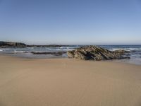 a beach covered in small rocks and water on a sunny day with sky above them