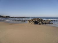 a beach covered in small rocks and water on a sunny day with sky above them