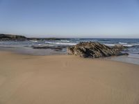 a beach covered in small rocks and water on a sunny day with sky above them