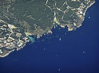 an aerial view of an island and some boats out in the water, some trees on the shore