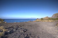 a black dirt road next to the ocean with a sign that says no parking or stairs