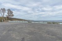 an empty parking lot on the side of the ocean shore with a bench sitting in the shade