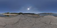 a lake with some rocks in front of it and a sky with clouds overhead it is an image that appears to be fish eye