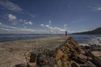 a lighthouse is on the edge of the water next to rocks and a seawall