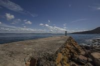 a lighthouse is on the edge of the water next to rocks and a seawall