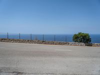 a parking lot on the corner of an empty road that has a sea in the background