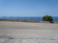 a parking lot on the corner of an empty road that has a sea in the background