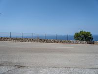 a parking lot on the corner of an empty road that has a sea in the background