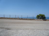 a parking lot on the corner of an empty road that has a sea in the background