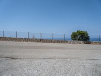 a parking lot on the corner of an empty road that has a sea in the background